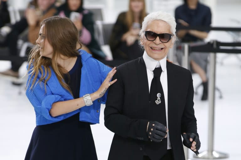 German fashion designer Karl Lagerfeld acknowledges the public along with British model Cara Delevingne at the end of the Chanel 2016 Spring/Summer ready-to-wear collection fashion show, on October 6, 2015 at the Grand Palais in Paris