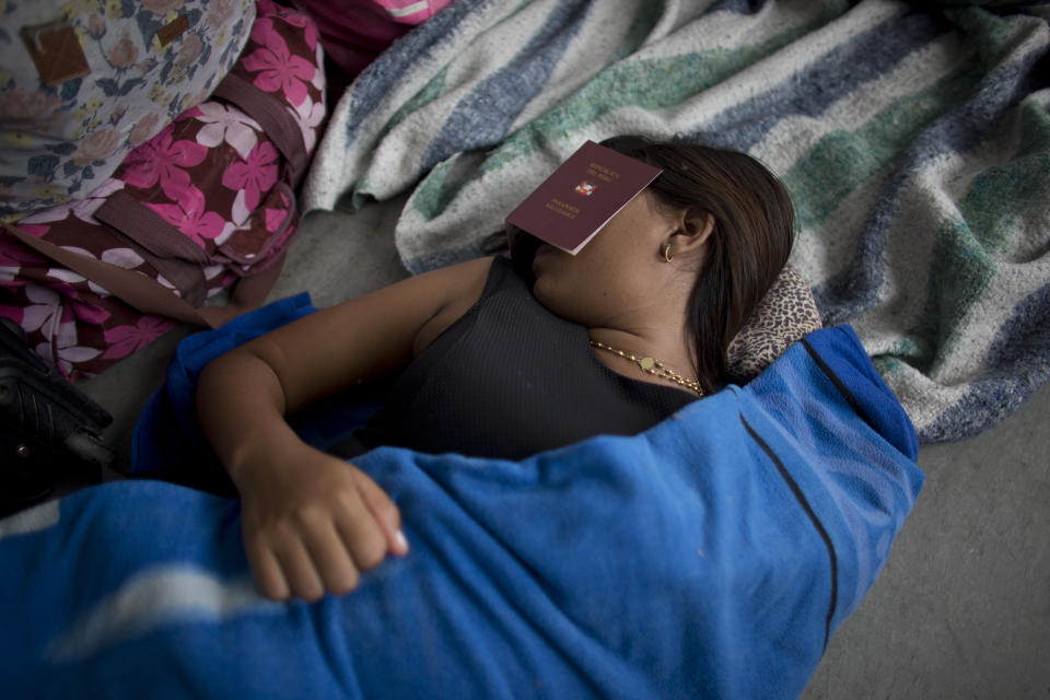 En esta imagen, tomada el 7 de septiembre de 2018, una mujer venezolana se cubre los ojos con un pasaporte "médico" peruano para dormir cerca de una oficina de inmigración en Tumbes, Perú. En la frontera, las autoridades migratorias peruanas entregan a los extranjeros un "pasaporte médico" tras pasar un control sanitario. (AP Foto/Ariana Cubillos)