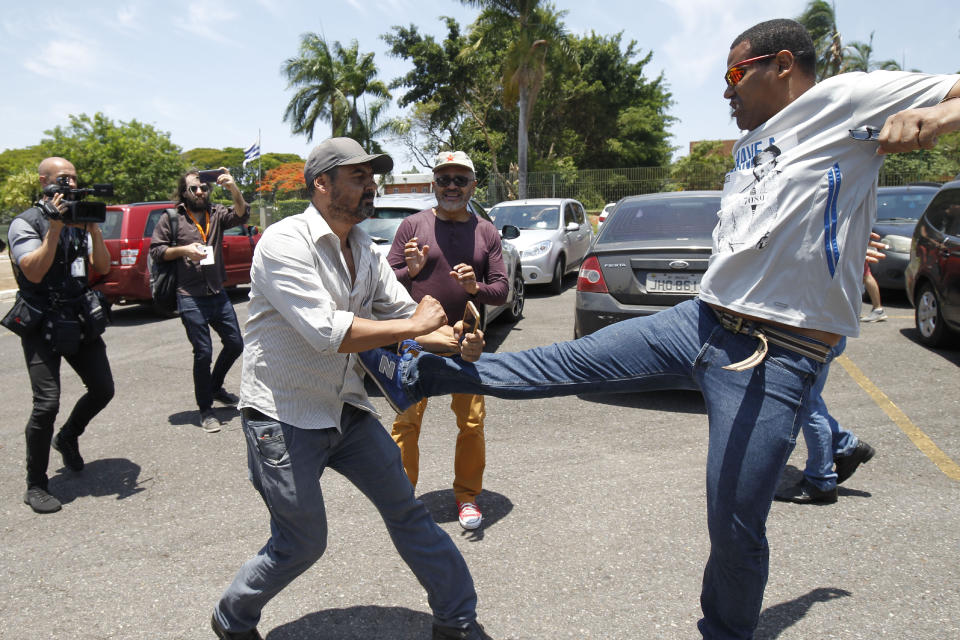 A supporter of Venezuelan President Nicolas Maduro kicks a supporter of Venezuelan opposition leader and self-proclaimed interim president Juan Guaido, outside the Venezuelan Embassy, in Brasilia, Brazil, Wednesday, Nov. 13, 2019. A group of people backing Guaido have occupied the nation's embassy in Brasilia. (AP Photo/Beto Barata)