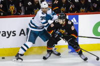 San Jose Sharks defenseman Mario Ferraro, left, checks Calgary Flames forward Andrew Mangiapane during the third period of an NHL hockey game in Calgary, Alberta, Saturday, March 25, 2023.(Jeff McIntosh/The Canadian Press via AP)