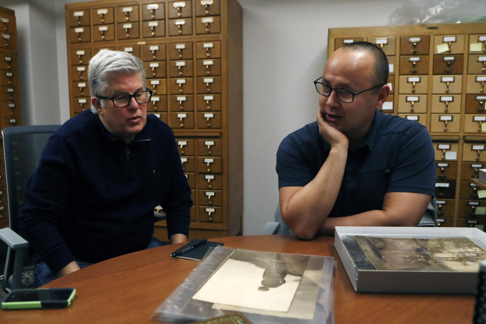 In this Thursday, Nov. 14, 2019 photo, Eric Hemenway, right, the director of archives and records for the Little Traverse Bay Band of Odawa Indians talks with collector Richard Port Jr., at the University of Michigan William Clements Library in Ann Arbor, Mich. Hemenway was examining the photographs acquired by the library in 2016 from Pohrt Jr. which represent some 80 indigenous groups. (AP Photo/Carlos Osorio)