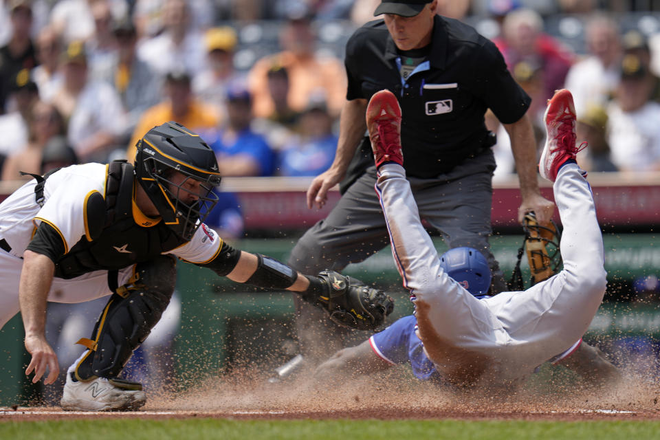 Texas Rangers' Adolis Garcia, right, slides safely past the tag attempt by Pittsburgh Pirates catcher Jason Delay to score with umpire Dan Iassogna making the call during the first inning of a baseball game in Pittsburgh, Wednesday, May 24, 2023. (AP Photo/Gene J. Puskar)