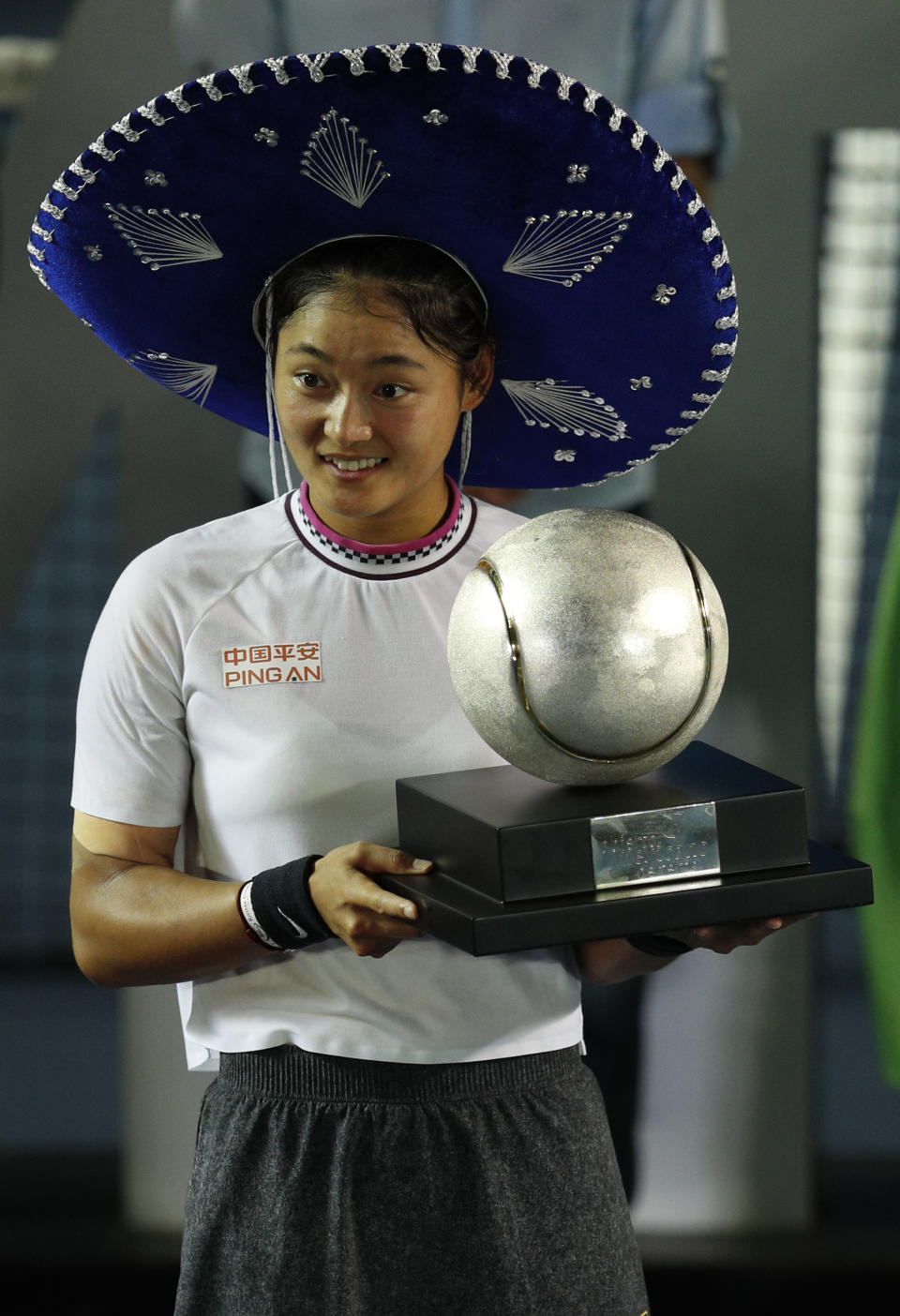 China's Yafan Wang holds her trophy and wears a Mexican sombrero after winning her Mexican Tennis Open final match against Sofia Kenin of the U.S., in Acapulco, Mexico, Saturday, March 2, 2019. (AP Photo/Rebecca Blackwell)