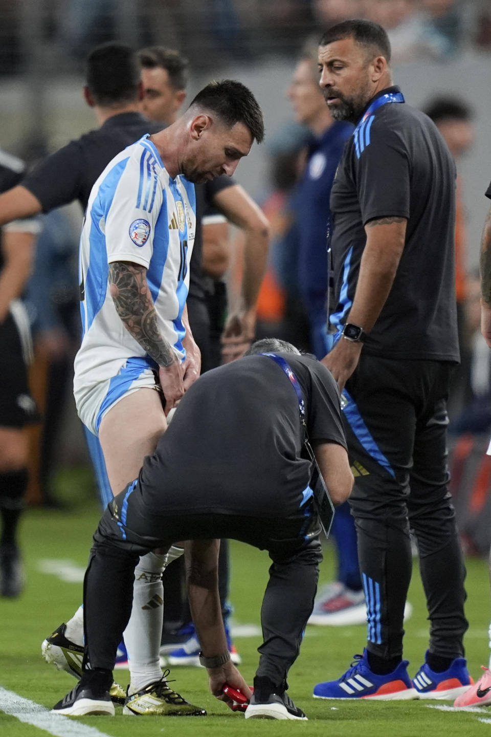 A team assistant tends to Argentina's Lionel Messi during a Copa America Group A soccer match against Chile in East Rutherford, N.J., Tuesday, June 25, 2024. (AP Photo/Julia Nikhinson)