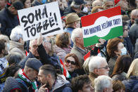 A woman holds a banne that read "Never Again" during a march marking the 65th anniversary of the 1956 Hungarian revolution, in Budapest, Hungary, Saturday, Oct. 23, 2021. Thousands of supporters of Prime Minister Viktor Orban, who is expected to deliver a speech marking the 65th anniversary of the 1956 Hungarian revolution, march in Budapest, Hungary to demonstrate loyalty to his right-wing government. (AP Photo/Laszlo Balogh)