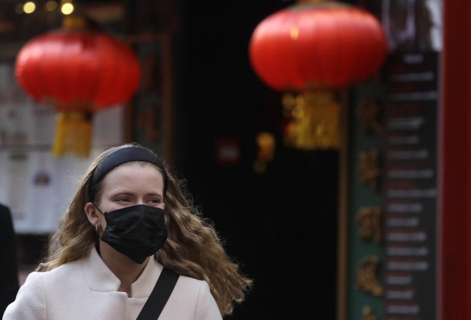 A woman wears a mask as she walks near China Town in London, Friday, Feb. 7, 2020. The director-general of the World Health Organization says a drop in the number of new coronavirus cases for two days is “good news” but cautions against reading too much into that. China reported 31,161 cases in mainland China in its update Friday. (AP Photo/Kirsty Wigglesworth)