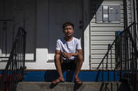 Bawi UK, 22, sits on the front steps of his home in Providence, R.I., Saturday, Sept. 26, 2020. UK was a small child when his parents fled Myanmar, leaving him and his siblings to be cared for by their maternal grandmother. UK said the family suffered discrimination as Christians in a predominantly Buddhist nation. The military government was also trying to forcibly conscript his father. "To run for office, you had to be a Buddhist; to rent a house, you had to be Buddhist," said UK, a social work student at Rhode Island College and a youth leader at the Refugee Dream Center, an advocacy organization in Providence. (AP Photo/David Goldman)