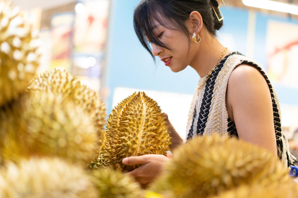 Young Asian female holding durian in hands