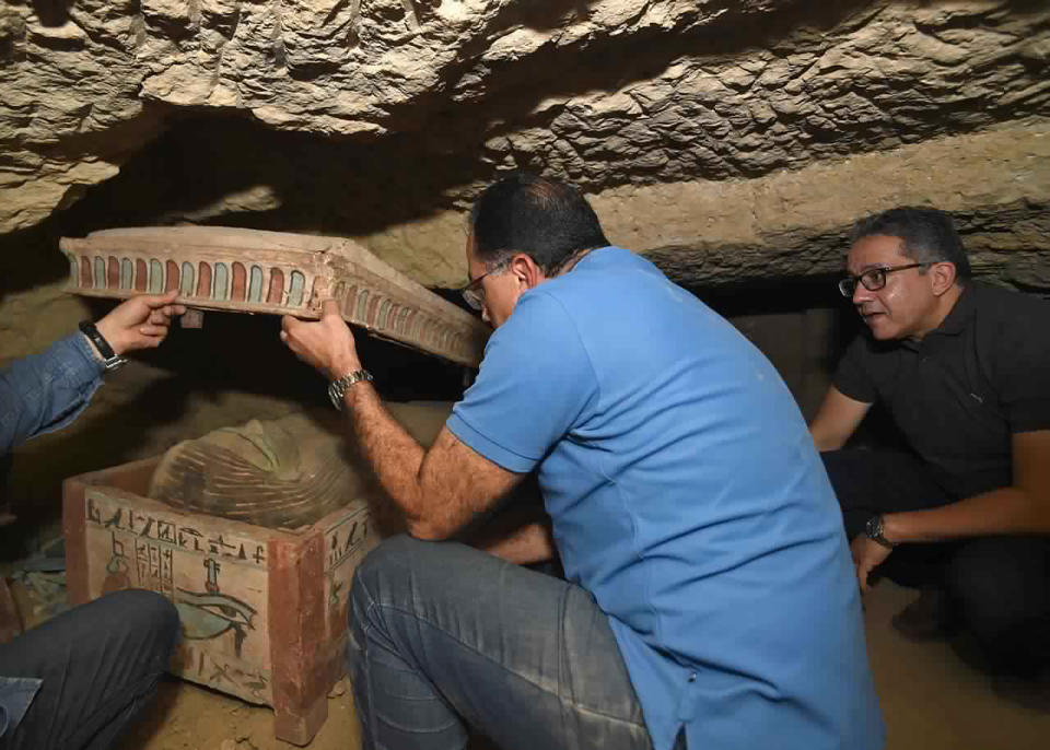 This undated photo provided by the Egyptian Ministry of Tourism and Antiquities shows archeologists opening a sarcophagus unearthed in a vast necropolis south of Cairo, that is part of a recent discovery authorities announced Monday, Oct. 19, 2020, in Saqqara, south of Cairo, Egypt. The Tourism and Antiquities Ministry said in a statement that archaeologists found a “large number” of colorful, sealed sarcophagi buried more than 2,500 years ago. (Ministry of Tourism and Antiquities via AP)