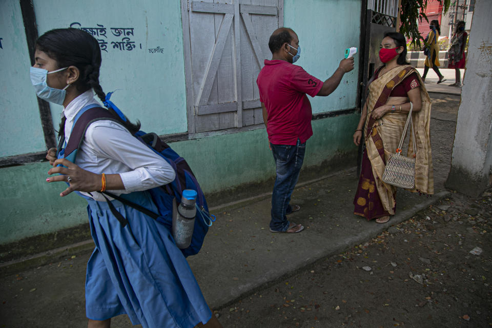 An employee checks the temperature of a teacher as schools in north-eastern Assam state reopen after being closed for months due to the coronavirus pandemic in Gauhati, India, Monday, Nov. 2, 2020. (AP Photo/Anupam Nath)