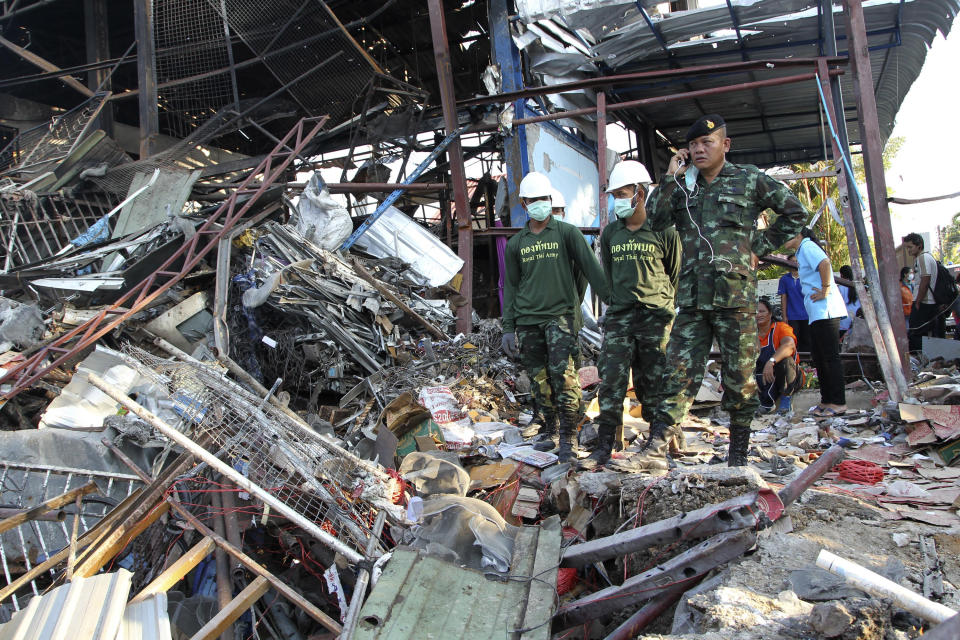 Thai soldiers stand next to a crater created by a bomb explosion at a scrap shop in Bangkok, Thailand, Wednesday, April 2, 2014. Workers at the shop accidentally detonated a large bomb believed to have been dropped during World War II, killing at least seven people and injuring 19 others, police said. (AP Photo/Apichart Weerawong)