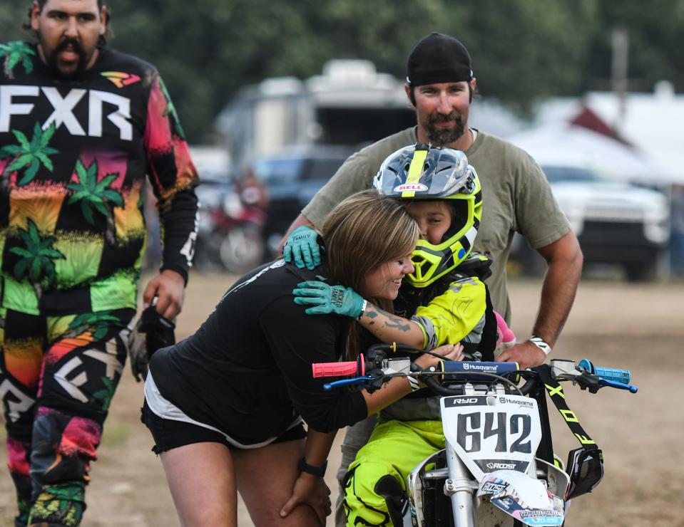 Amanda Carlon of Wayland hugs daughter Ryder, 8, before she competes in a motocross race Tuesday, July 12, 2022, at the Eaton County Fair in Charlotte.  Ryder has been racing since she was two. Behind Ryder is her dad, Bill.