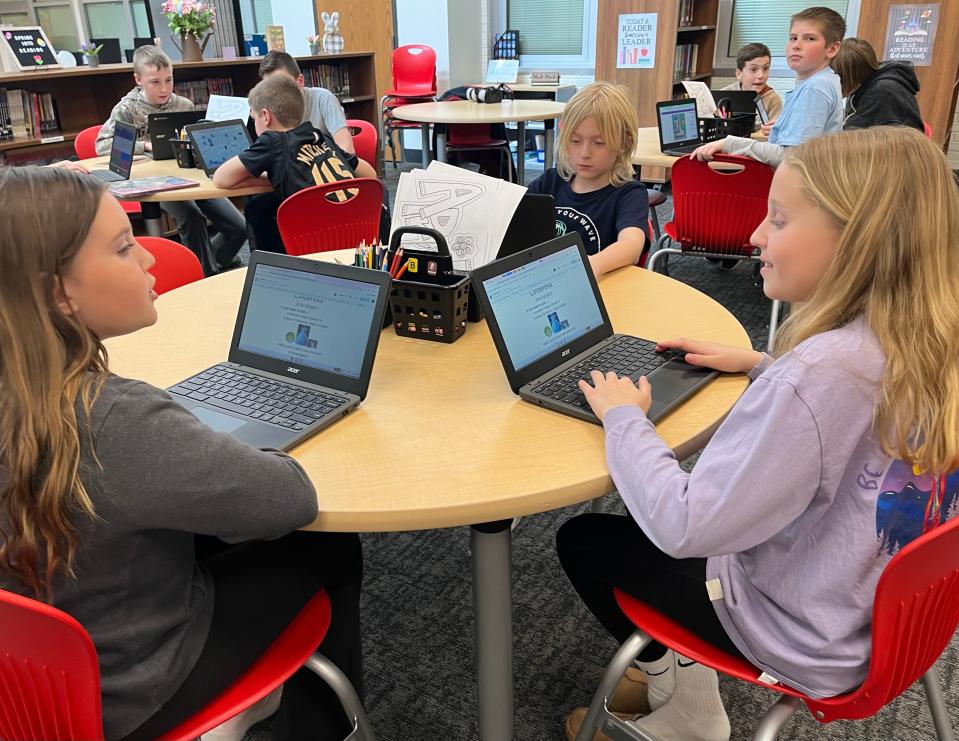 Johnstown Intermediate School fifth-graders Annabelle Parpart and Camryn Buchanan create flyers during a 30-minute period Wednesday with librarian Brandie Peterman.