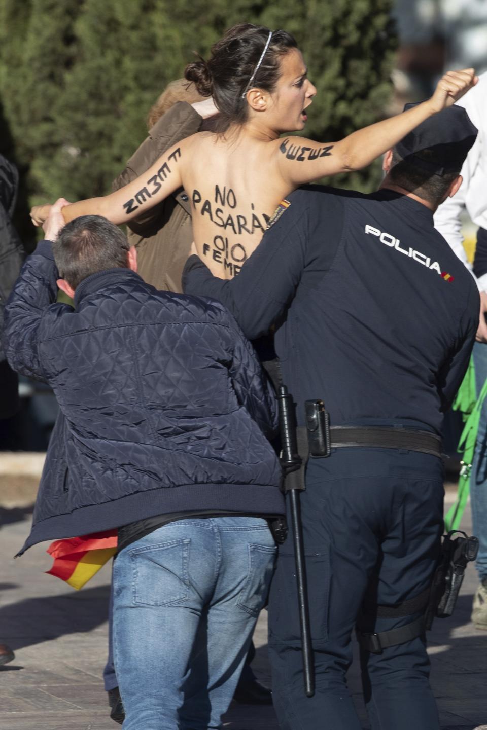 An activist from FEMEN group is removed from the stage as she shouts slogans against Spain's far-right VOX party election campaign in Madrid, Spain, Friday, April 26, 2019. Appealing to Spain's large pool of undecided voters, top candidates on both the right and left are urging Spaniards to choose wisely and keep the far-right at bay in Sunday's general election. (AP Photo/Bernat Armangue)