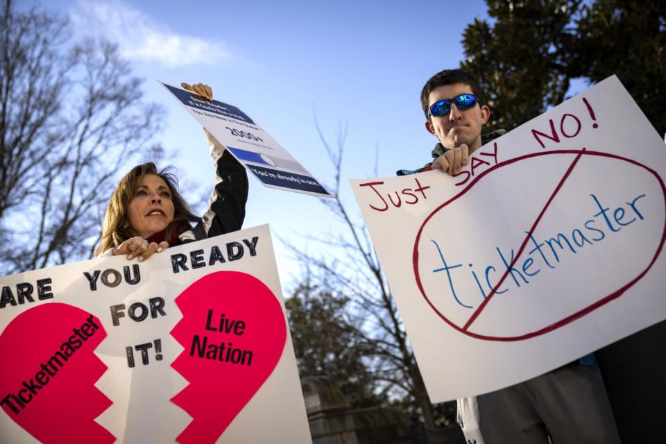 Two people hold signs protesting the ticketing industry