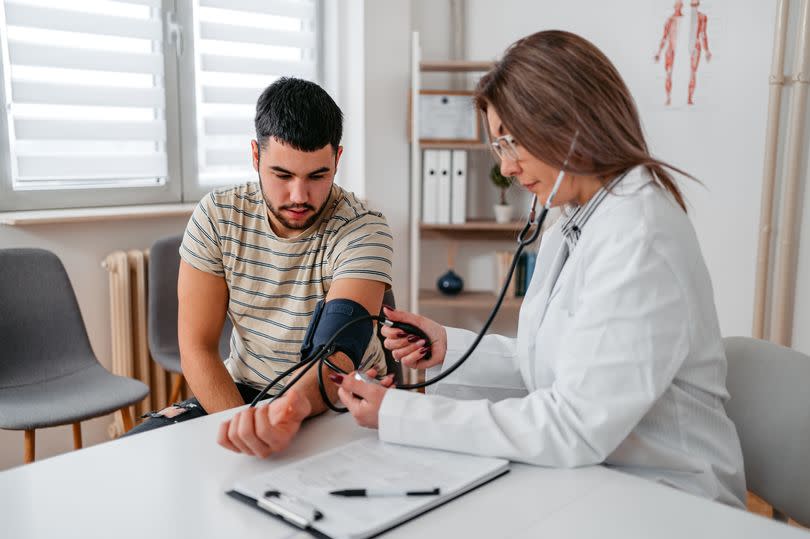 Female doctor measuring blood pressure of a teenage patient in the doctor's office.