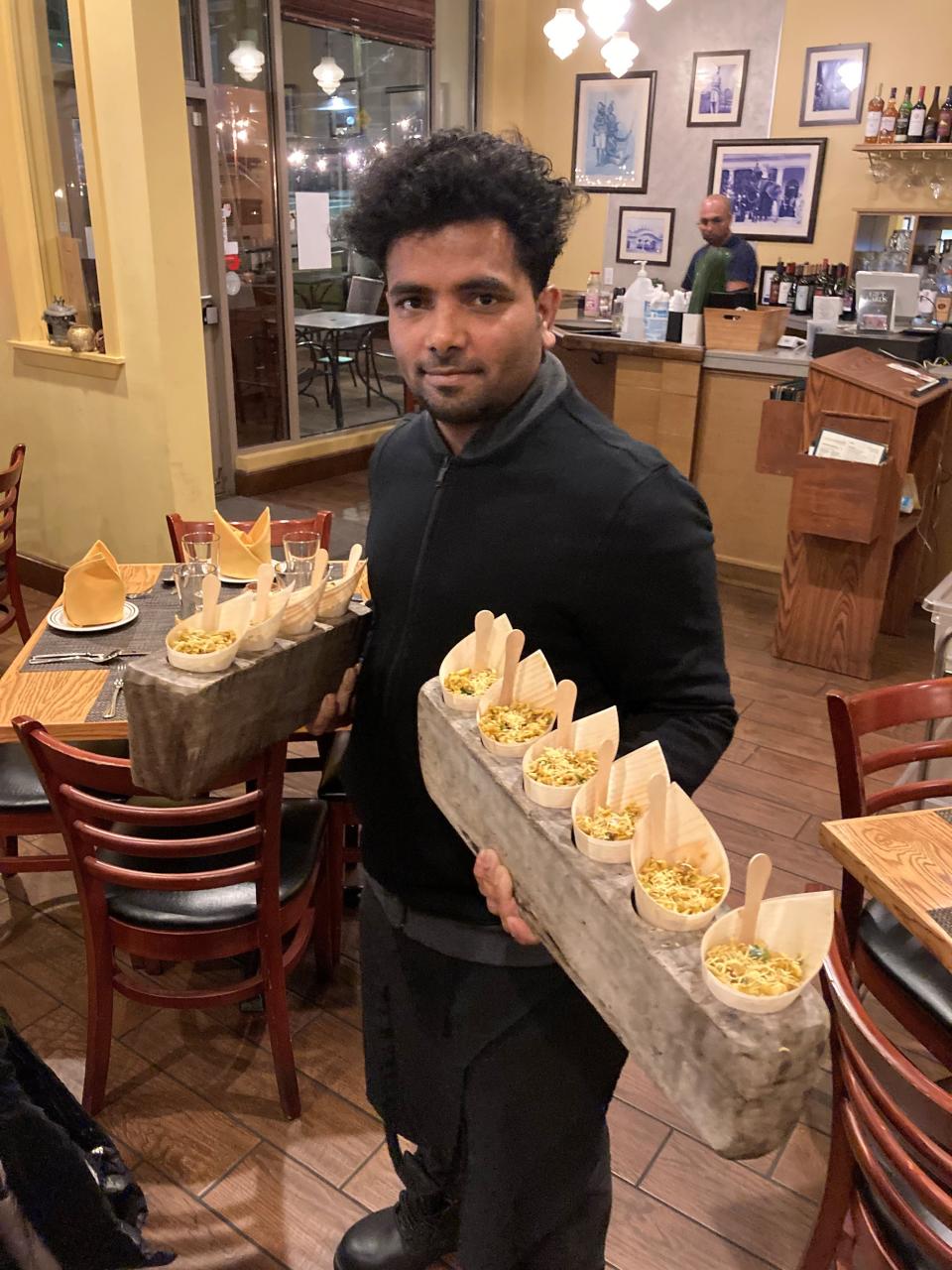 A waiter at Chutney Masala in Irvington serving Jhaal Moori, a street food snack made of puffed rice and an assortment of spices and vegetables. Photographed November 2021.