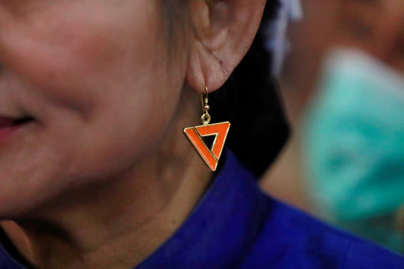 A supporter of Future Forward Party wears a party's logo earring, at the party's headquarters in Bangkok