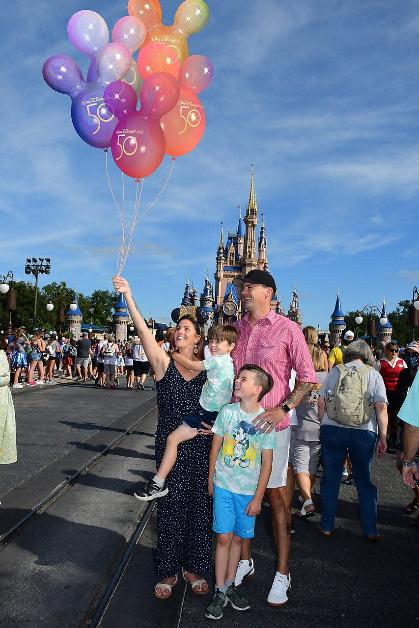tarah and her family posing for a magic photoshoot in front of cinderella castle disney world