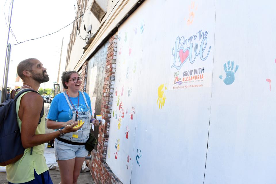 Alex RiverFete visitors like Howard Desselle (left) were encouraged to leave handprints, baby hand or feet prints - or even pet paw prints - on the wall as part of the "Share the Love" project that was a collaboration between the  Mayor's Office of Economic Development and downtown business Kinetix Solutions. Mary Kathryn Merrill (right), customer service representative at Kinetix Solutions, headed up the project.