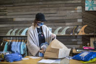 Emma Hamlet prepares orders received online to be picked up at the Long Beach Surf Shop store her family owns, Wednesday, May 27, 2020, in Long Beach, N.Y. Long Island has become the latest region of New York to begin easing restrictions put in place to curb the spread of the coronavirus as it enters the first phase of the state's four-step reopening process. (AP Photo/Mary Altaffer)
