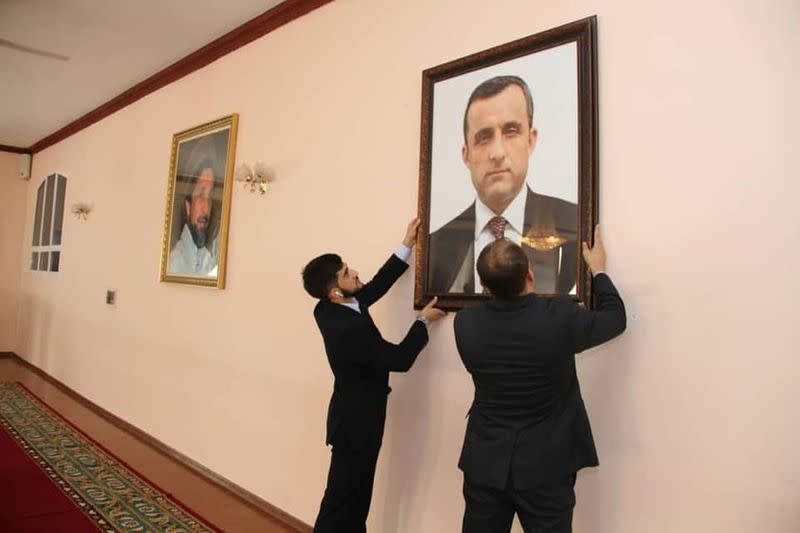 Afghan embassy staff hang a portrait of Afghan First Vice President Amrullah Saleh on the wall at the embassy in Dushanbe