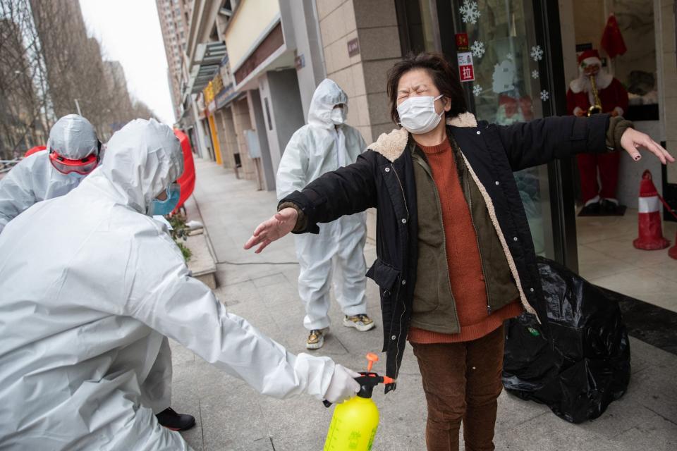 A woman who has recovered from the COVID-19 is disinfected by volunteers as she arrives at a hotel for a 14-day quarantine (AFP via Getty Images)