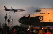 The space shuttle Endeavour sits in a strip mall as a Hawaiian Airlines jet approaches a runway at Los Angeles International Airport in Los Angeles, Friday, Oct. 12, 2012. Endeavour's 12-mile road trip kicked off shortly before midnight Thursday as it moved from its Los Angeles International Airport hangar en route to the California Science Center, its ultimate destination, said Benjamin Scheier of the center. (AP Photo/Jae C. Hong)