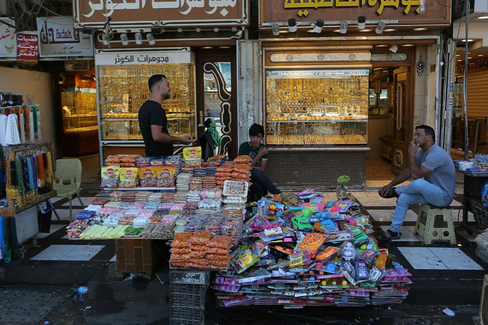 In this Wednesday, May 21, 2019, photo, street vendors and shop owners wait for customers outside the shrine of Imam Moussa al-Kadhim in Kadhimiya district in north Baghdad, Iraq. Many shop owners in the Shiite holy neighborhood of Kadhimiya, have seen their sales drop sharply over the past year since U.S. President Donald began reimposing sanctions on Iran, home to the largest number of Shiite Muslims around the world. (AP Photo/Khalid Mohammed)