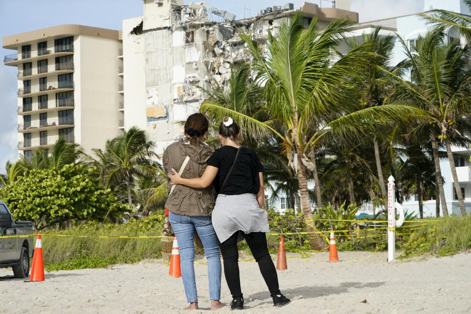 Maria Fernanda Martinez, left, and Mariana Corderiro, right, of Boca Raton, Fla., stand outside of a 12-story beachfront condo building which partially collapsed, Friday, June 25, 2021, in the Surfside area of Miami. The apartment building partially collapsed on Thursday.(AP Photo/Lynne Sladky)