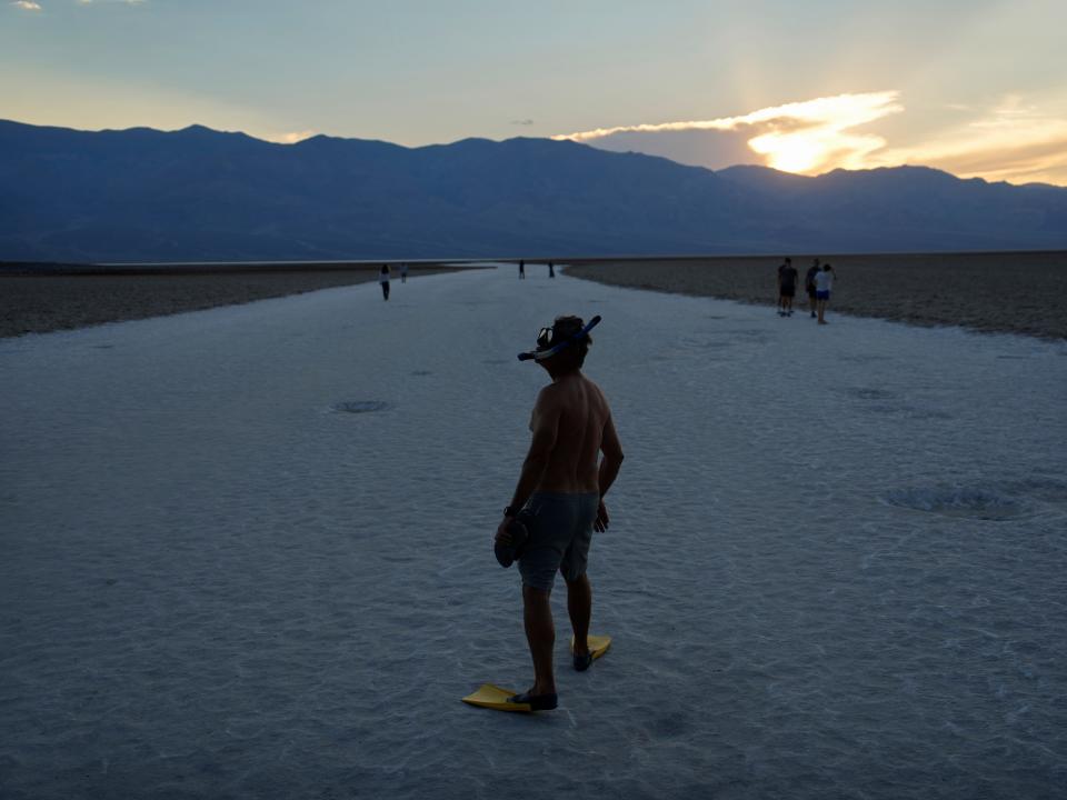 Marko Leszczuk walks along the salt flats at Badwater Basin as the sun sets, Sunday, July 16, 2023, in Death Valley National Park, Calif.
