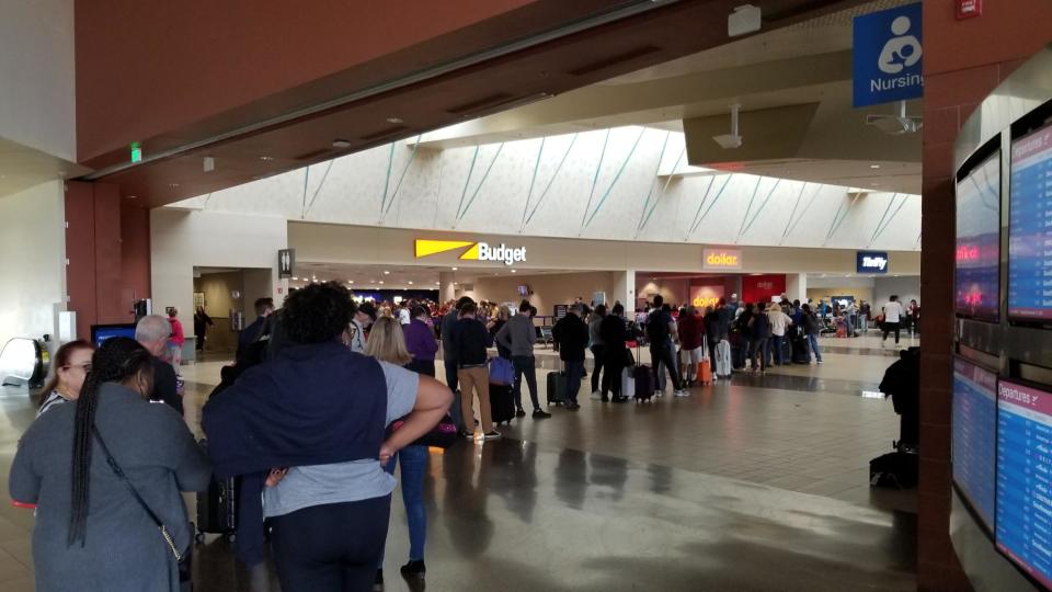 Travelers wait in a snaking line at the Phoenix Sky Harbor International Airport rental car center on Dec. 27, 2022.