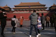 People pose for pictures and stand outside the main entrance of the Forbidden City where a notice is seen saying that the place is closed to visitors for the safety concern following the outbreak of a new coronavirus, in Beijing