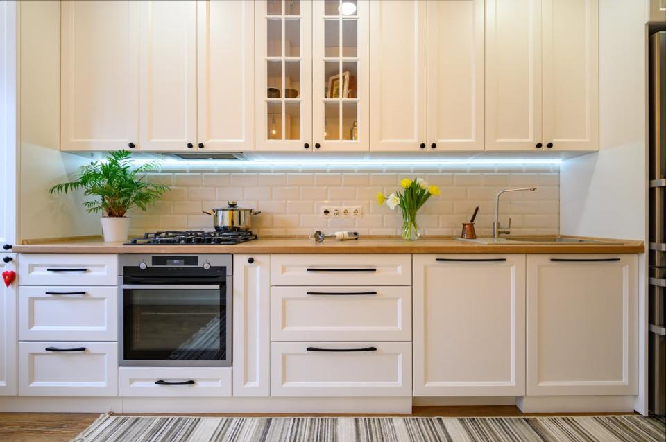 Modern kitchen interior with white cabinets and under cabinet lighting. 