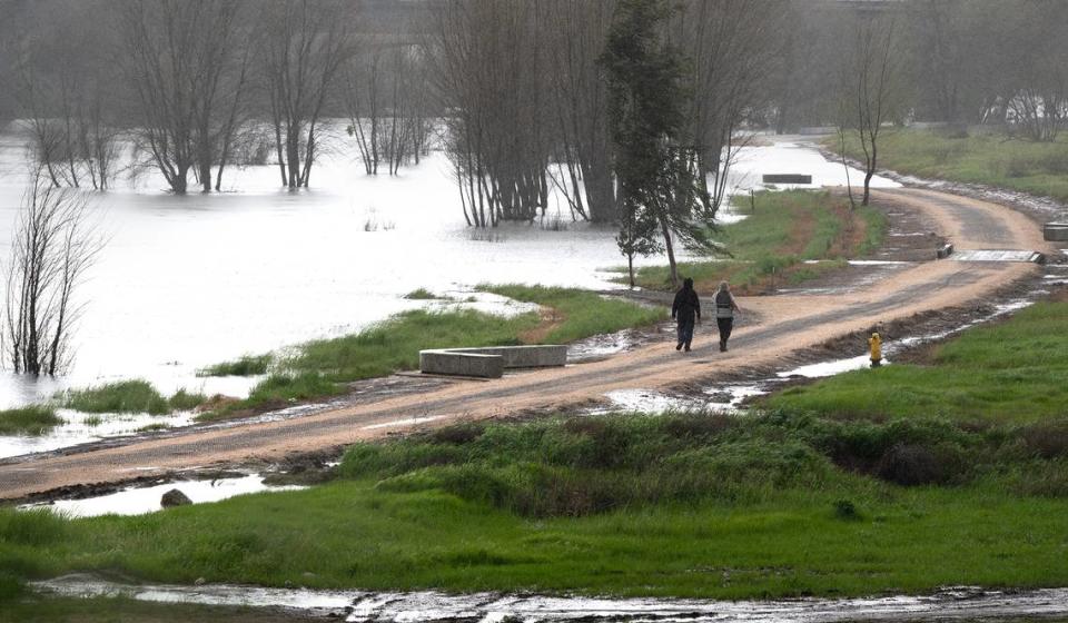 The walking path in the Tuolumne River Regional Park is partially submerged by water from the Tuolumne River in Modesto, Calif., Tuesday, March 21, 2023.