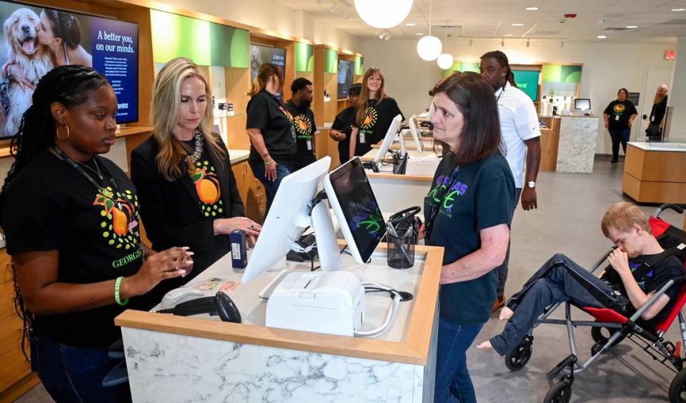 Leslie Johns, right, was the first customer to make a purchase at the Trulieve medical marijuana dispensary in Macon Friday morning. Johns was making the purchase of cannabis oil for her son Darrell “Peanut” Johns who was born with hydrocephalus and epilepsy.