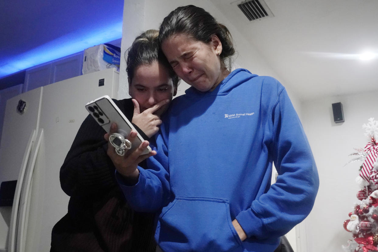 Melanie Rolo Gonzalez, right, and her sister Merlyn hold a video call with their mother and grandfather back home in Cuba, from the home of a family friend in Daytona, Florida, Tuesday, Jan. 3, 2023. (AP Photo/Marta Lavandier)