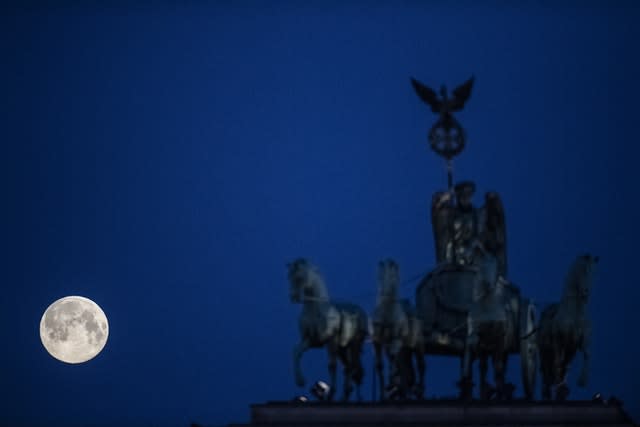 The supermoon sets behind the Brandenburg Gate