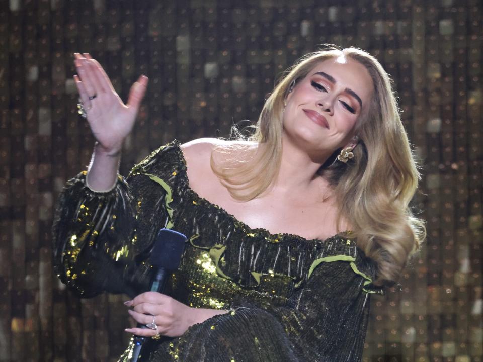 Adele with head tilted, eyes slightly shut, and hand motioning in the air.