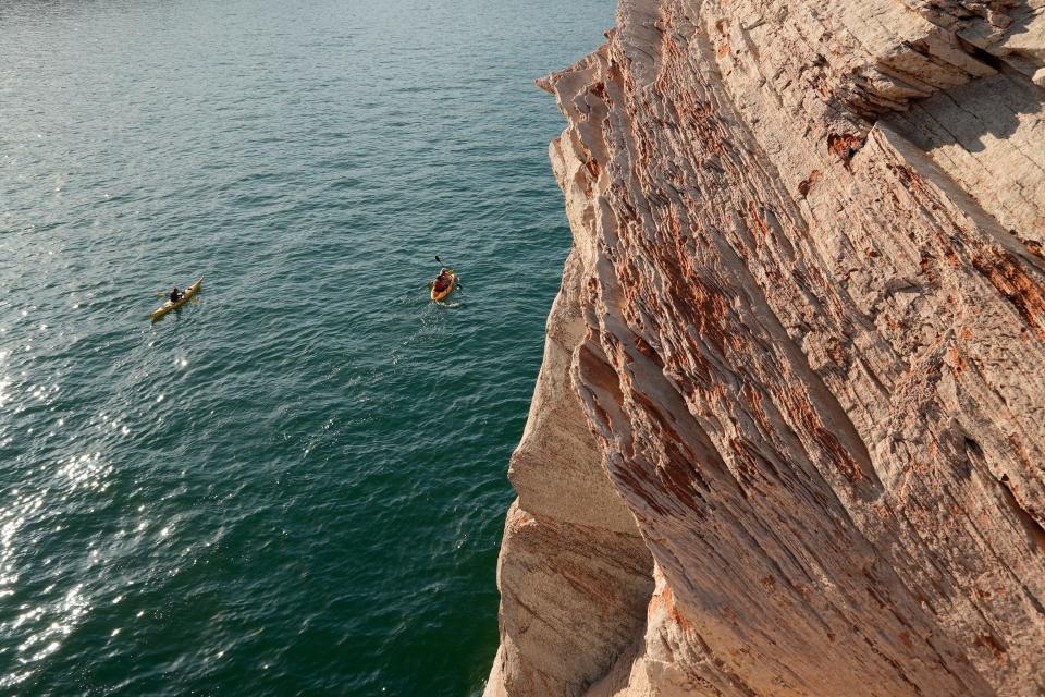 \Kayakers paddle past bathtub rings showing how low Lake Powell levels have declined June 7, 2022, in Page, Ariz. As America's large reservoirs on the Colorado River drop to record-low levels, fish are among those suffering the impact.