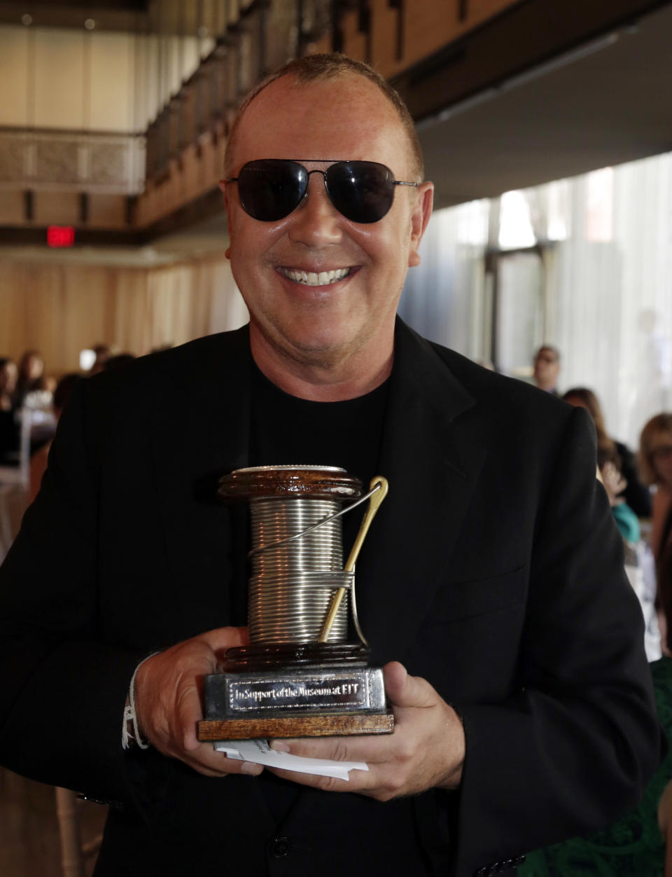 Designer Michael Kors holds 2013 The Couture Council Award for Artistry of Fashion presented by actress Hilary Swank during a luncheon in the David H. Koch Theater of New York's Lincoln Center, Wednesday, Sept. 4, 2013. The luncheon benefits the museum at the Fashion Institute of Technology in New York. (AP Photo/Richard Drew)