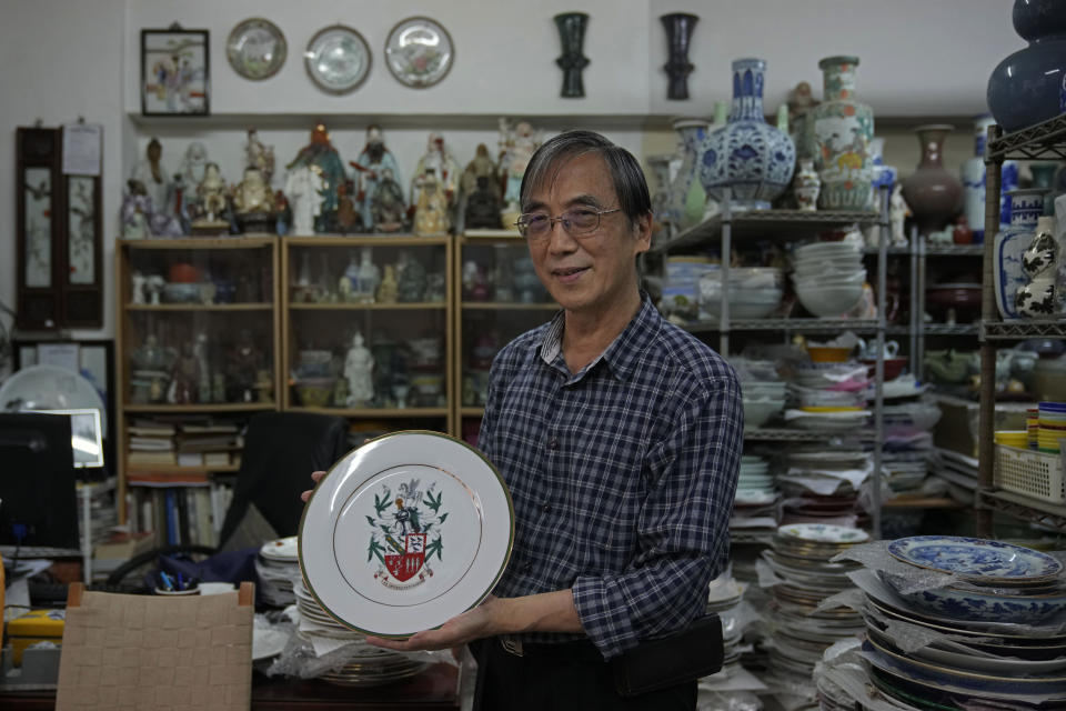 Joseph Tso, owner of Yuet Tung China Works, Hong Kong's last hand-painted porcelain factory, holds a plate with UK royal print in Hong Kong, Wednesday, June 8, 2022. Tso, the third-generation owner of the factory, and his small team are among the few people in Hong Kong who have mastered the traditional technique of painting “guangcai,” or Canton porcelain. (AP Photo/Kin Cheung)