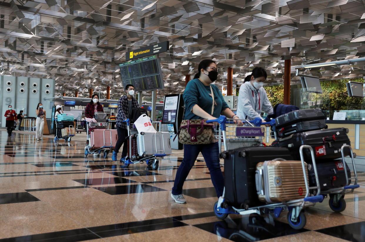 Travellers walk with their luggage at the Changi Airport in Singapore. 