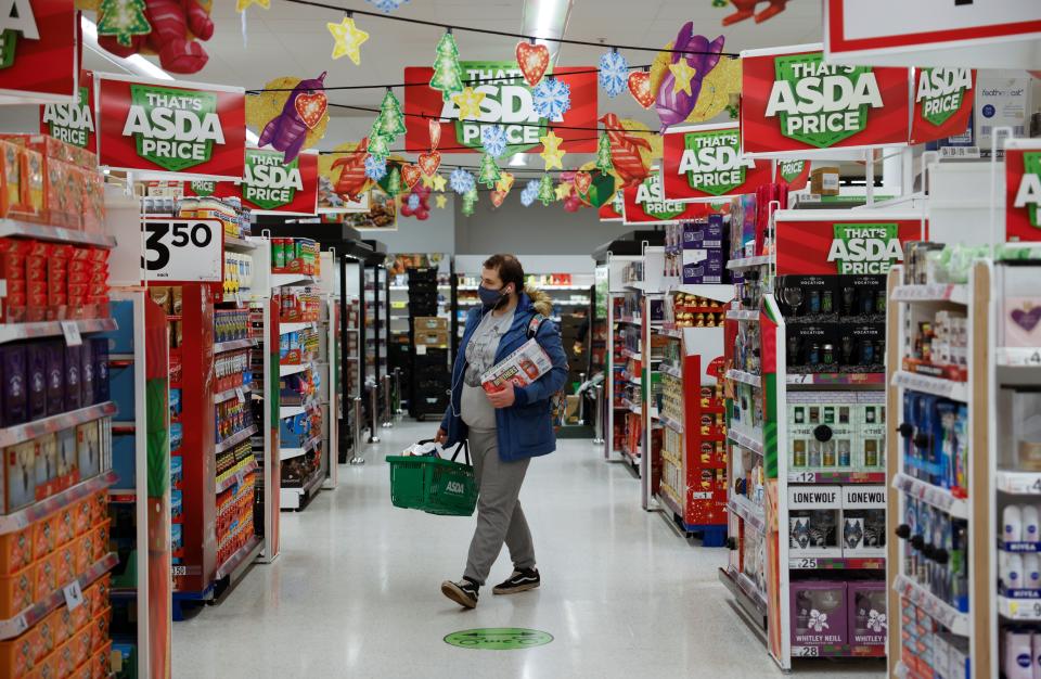 A shopper wearing a face mask or covering due to the COVID-19 pandemic, carries goods in a shopping basket inside an ASDA supermarket in Walthamstow in north east London on December 22, 2020. - The British government said Tuesday it was considering tests for truckers as part of talks with French authorities to allow the resumption of freight traffic suspended due to a new strain of coronavirus. Britain was plunged into fresh crisis last week with the emergence of a fresh strain of the virus, which is believed to be up to 70 percent more transmissible than other forms. (Photo by Tolga Akmen / AFP) (Photo by TOLGA AKMEN/AFP via Getty Images)