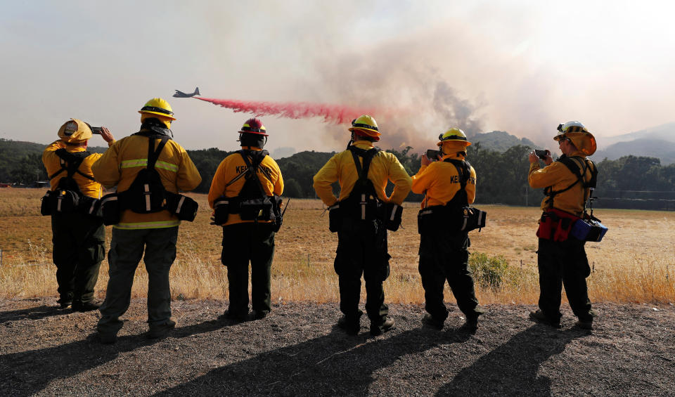 Firefighters watch as an air tanker drops fire retardant to protect homes along the crest of a hill at the River Fire near Lakeport, California.