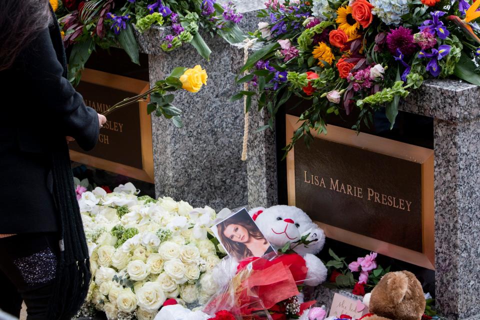 A mourner places a rose on Lisa Marie Presley’s grave after her celebration of life at Graceland in Memphis, Tenn., on Sunday, January 22, 2023. 