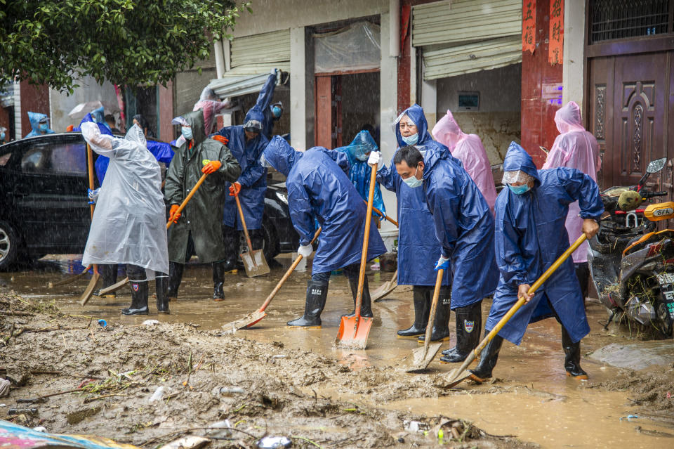 In this photo released by China's Xinhua News Agency, people shovel debris and mud from a road in Liulin Township of Suixian County in central China's Hubei Province, Friday, Aug. 13, 2021. Flooding in central China continued to cause havoc in both cities and rural areas, with authorities saying Friday that more than 20 people had been killed and another several were missing. (Wu Zhizun/Xinhua via AP)