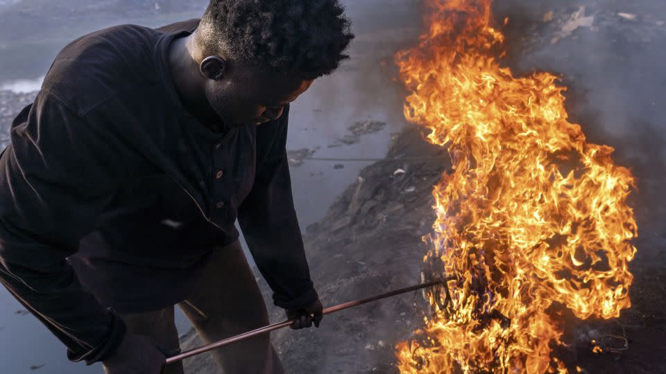 Simon Aniah, 24, burns scrap electrical cables to recover copper by the Korle Lagoon in Accra, Ghana, February 9, 2023. - Muntaka Chasant for Fondation Carmignac