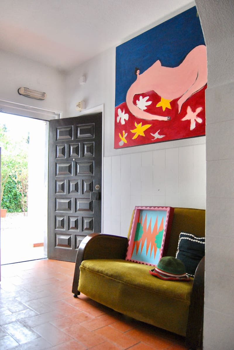 Dark wood door at entryway with green couch and colorful artwork.