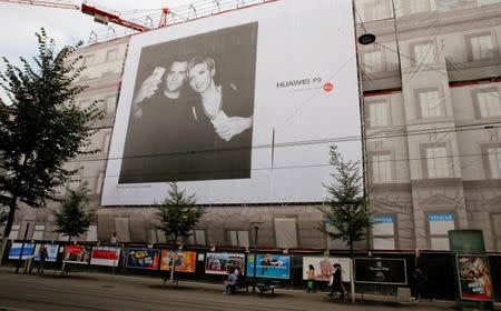 FILE PHOTO: People walk past a giant advertizing poster of Chinese telecommunications company Huawei at the Bahnhofstrasse in Zurich, Switzerland July 15, 2016. REUTERS/Arnd Wiegmann/File Photo